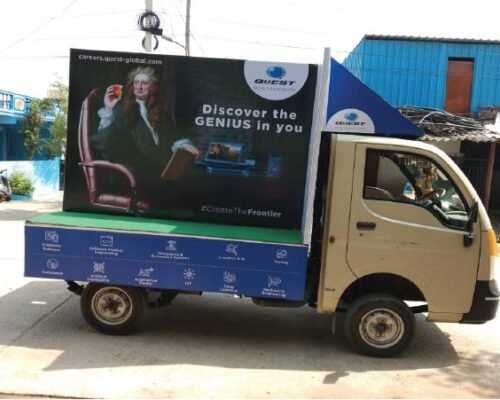 Truck advertising vehicle promoting QuEST Global with Newton-themed “Discover the Genius in You” campaign and digital career graphics.